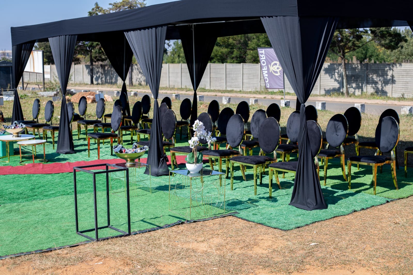 Dignified graveside setup with a black marquee and black-and-gold chairs