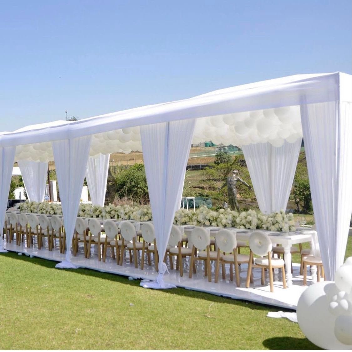 White draped marquee with wood crossback chairs and a balloon garland